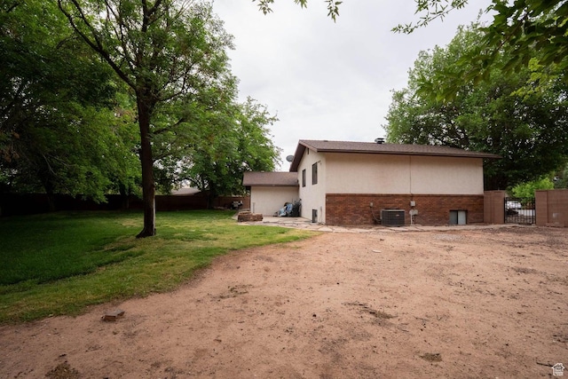 944 Gardenia Cir, St George, UT 84790 - rear view of house with a lawn, brick siding, fence, central air condition unit, and a gate