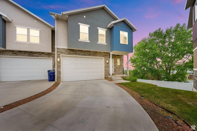 view of property with stone siding, a garage, stucco siding, concrete driveway, and a front yard