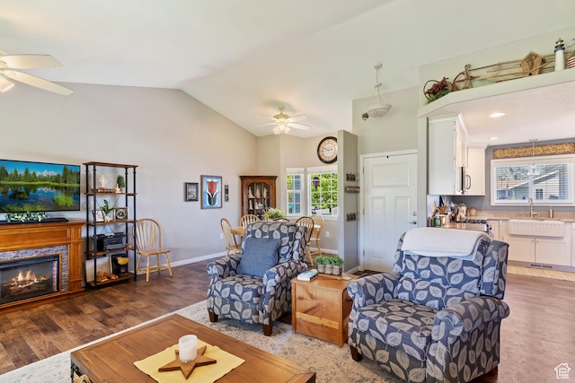 living room featuring a ceiling fan, baseboards, high vaulted ceiling, and wood finished floors