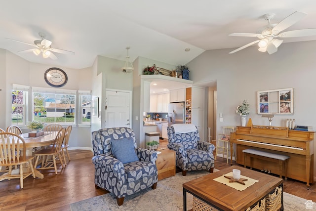 living room with baseboards, wood finished floors, a ceiling fan, and high vaulted ceiling