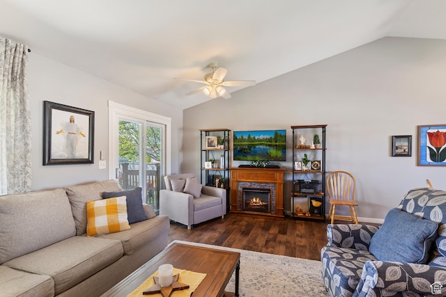 living area featuring a lit fireplace, ceiling fan, lofted ceiling, and dark wood-type flooring