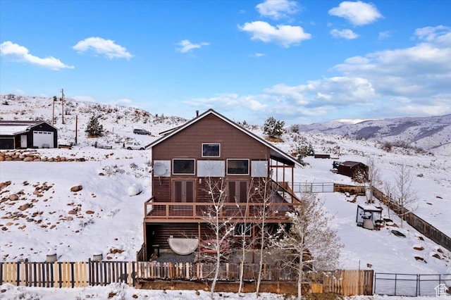snow covered back of property featuring fence private yard and a deck