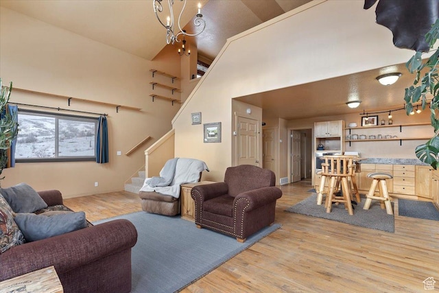 living area with a high ceiling, light wood-type flooring, visible vents, baseboards, and stairs