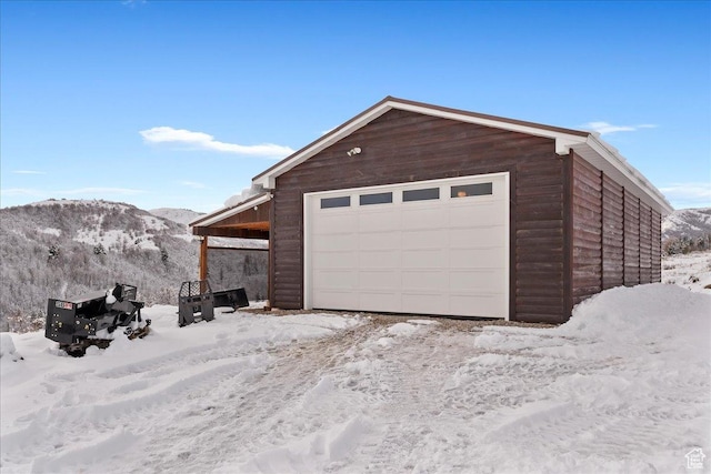 snow covered garage with a mountain view and a detached garage