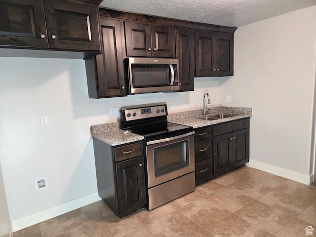 125 E Christley Ln, Elk Ridge, UT 84651 - kitchen featuring appliances with stainless steel finishes, a sink, baseboards, light stone countertops, and dark brown cabinetry