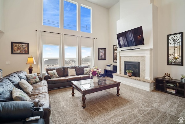 living room with carpet flooring, a high ceiling, and a glass covered fireplace