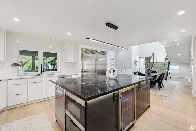 3520 S Westwood Dr E, Millcreek, UT 84109 - kitchen featuring beverage cooler, a sink, light wood-type flooring, white cabinetry, and built in appliances