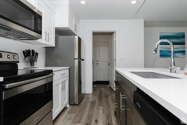 2396 N 150 E, North Logan, UT 84341 - kitchen featuring light countertops, a sink, white cabinetry, light wood-style floors, and stainless steel appliances