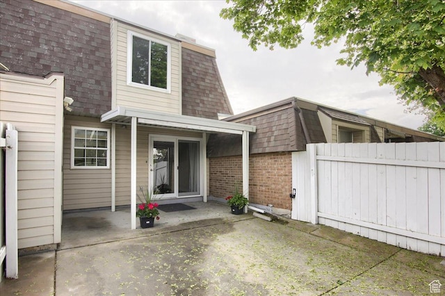 571 N 200 W, Bountiful, UT 84010 - rear view of house with mansard roof, a patio area, brick siding, and roof with shingles