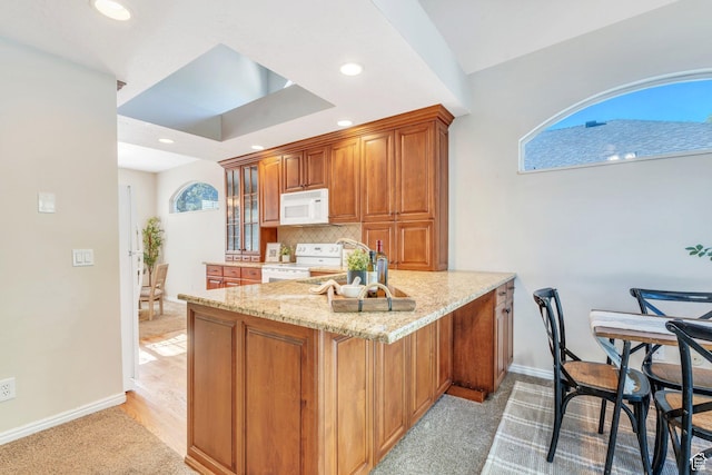 12532 S Blacksmith Ln, Draper, UT 84020 - kitchen with a peninsula, white appliances, brown cabinets, light stone countertops, and baseboards