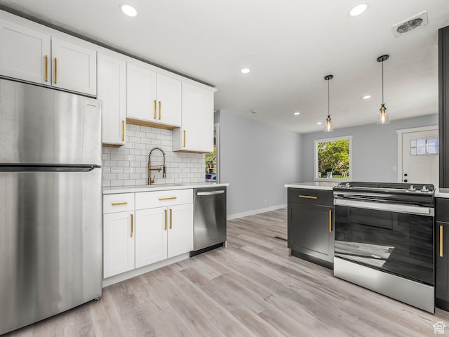kitchen with a sink, stainless steel appliances, visible vents, baseboards, and light countertops