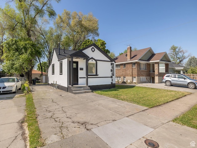 bungalow-style home featuring concrete driveway, stucco siding, and a front yard