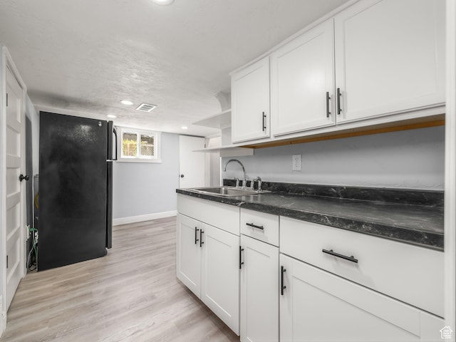 kitchen with freestanding refrigerator, open shelves, a sink, and white cabinets