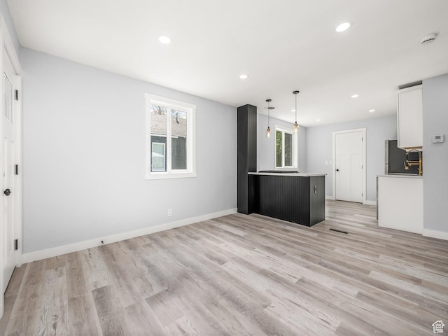 kitchen with light wood finished floors, white cabinetry, refrigerator, and recessed lighting