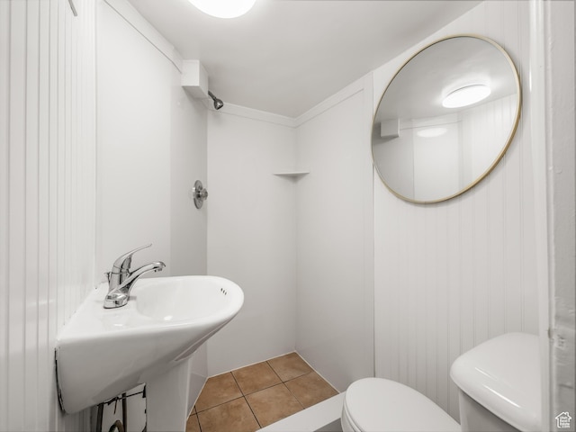 half bath featuring toilet, tile patterned flooring, and a sink