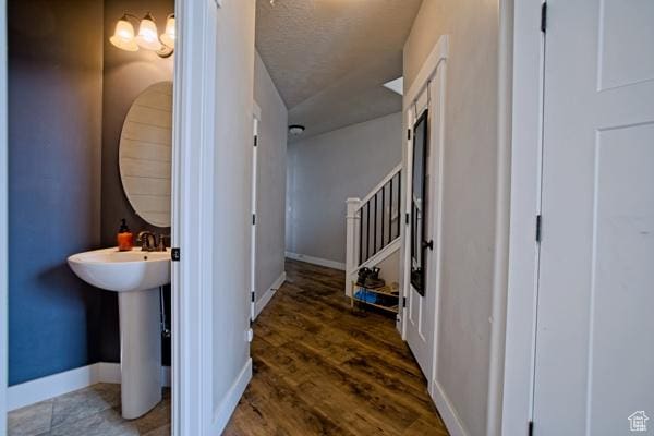 hallway featuring baseboards, a sink, and wood finished floors