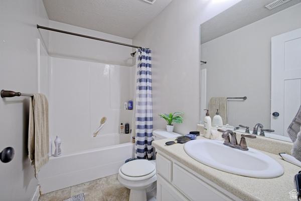 full bath with vanity, shower / tub combo with curtain, toilet, and visible vents