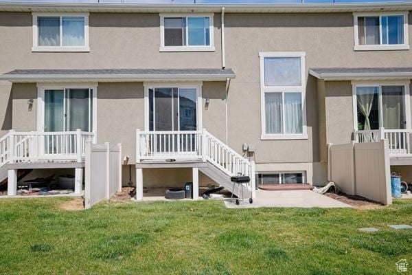 rear view of property with a lawn, stairway, and stucco siding