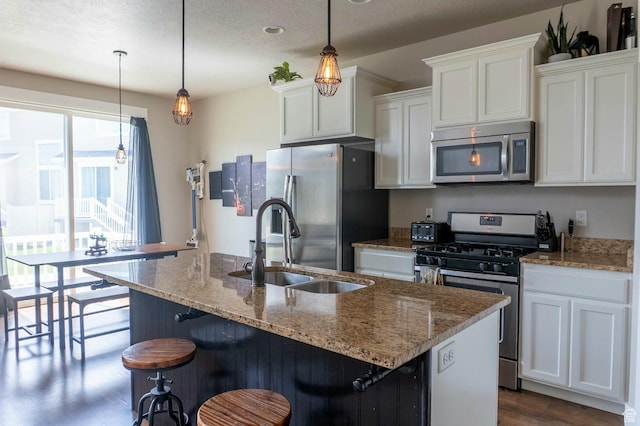 954 S 2040 W, Orem, UT 84059 - kitchen with appliances with stainless steel finishes, white cabinets, a kitchen island with sink, light stone countertops, and a kitchen bar