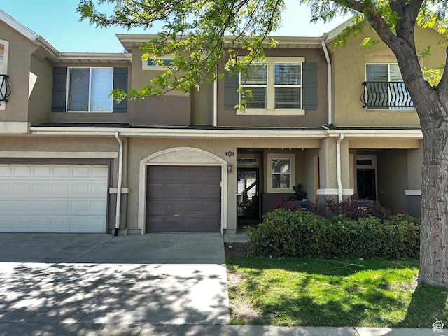 townhome / multi-family property featuring concrete driveway, stucco siding, and a garage