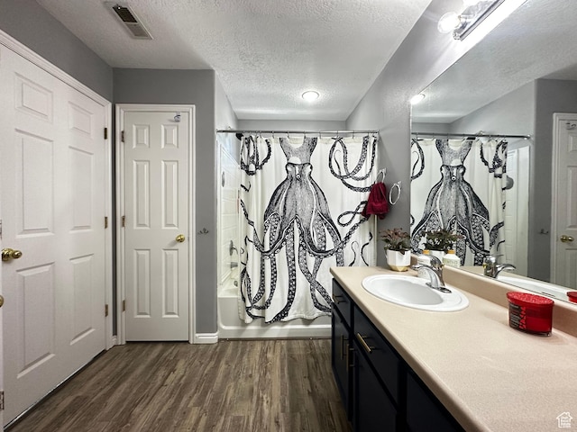 bathroom with vanity, a textured ceiling, visible vents, and wood finished floors