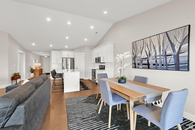 dining room featuring vaulted ceiling, baseboards, light wood-type flooring, and recessed lighting