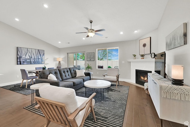 living room featuring baseboards, a glass covered fireplace, ceiling fan, and wood finished floors