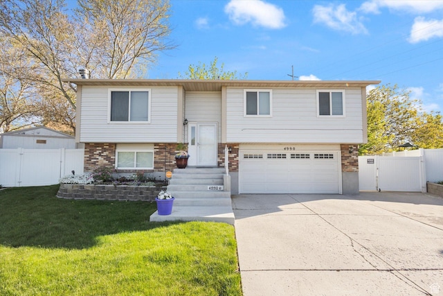 4990 S Hensley Cir, Taylorsville, UT 84129 - split foyer home with driveway, fence, an attached garage, a front yard, and a gate