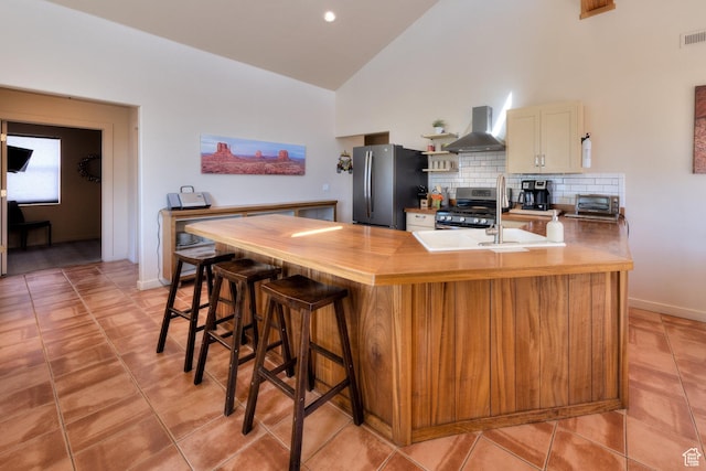 3686 S Spanish Valley Dr Unit K-2, Moab, UT 84532 - kitchen featuring a peninsula, stainless steel appliances, wall chimney range hood, high vaulted ceiling, and decorative backsplash