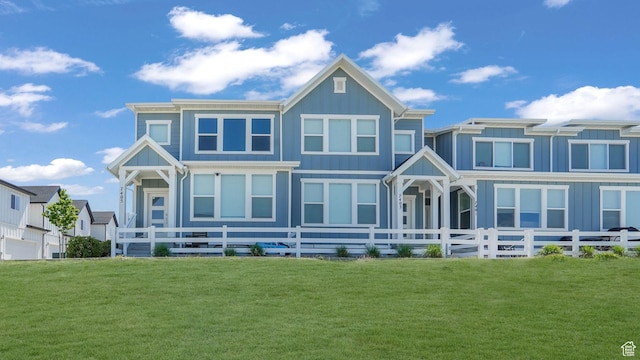 view of front of house featuring board and batten siding, a front yard, and fence private yard
