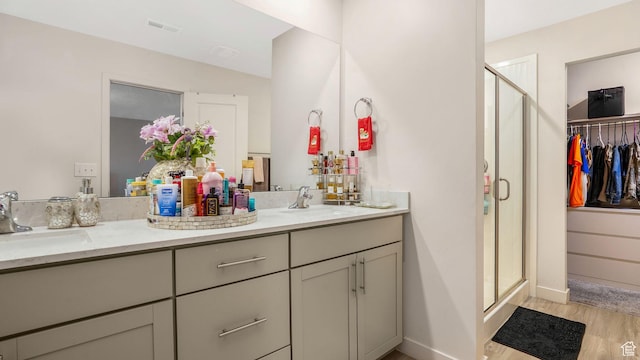 bathroom with visible vents, wood finished floors, a shower stall, and a sink