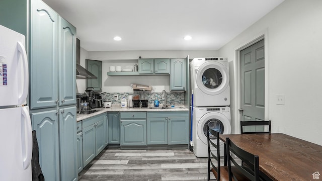 washroom with recessed lighting, a sink, stacked washer and dryer, light wood-style floors, and laundry area