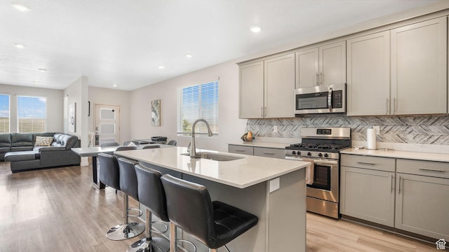 kitchen with open floor plan, a sink, appliances with stainless steel finishes, and gray cabinetry