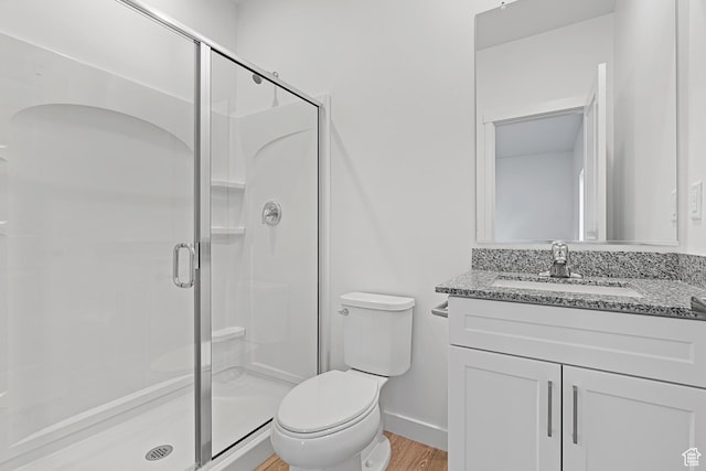 full bathroom with toilet, wood finished floors, vanity, a shower stall, and baseboards
