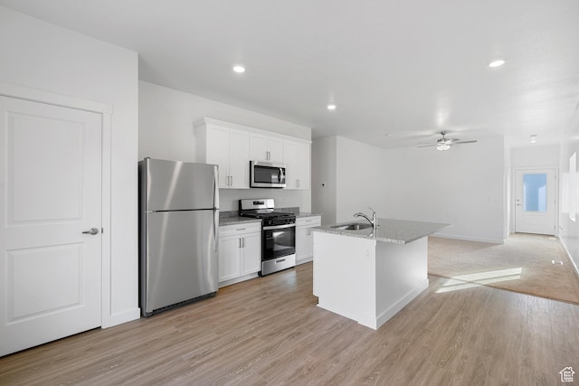 kitchen featuring a ceiling fan, a sink, a center island with sink, white cabinets, and appliances with stainless steel finishes