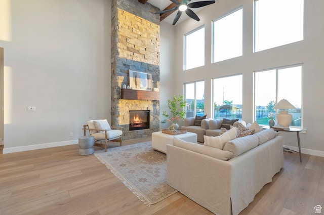 514 S 1450 W, Farmington, UT 84025 - living room with a stone fireplace, a high ceiling, light wood finished floors, ceiling fan, and baseboards