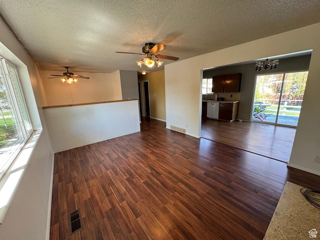 unfurnished living room featuring a textured ceiling, visible vents, ceiling fan with notable chandelier, and dark wood-type flooring
