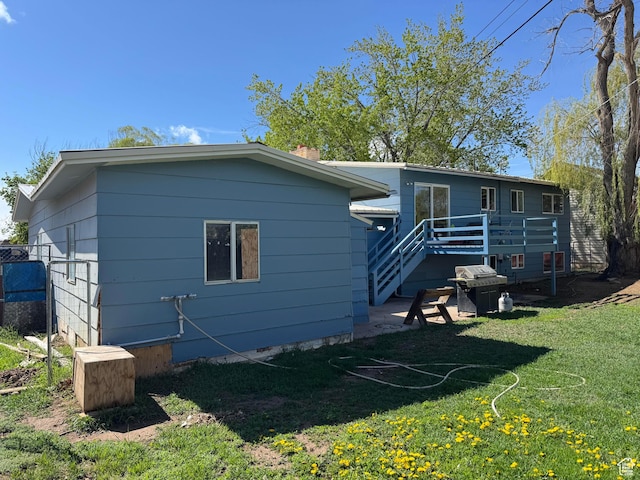 back of house featuring a wooden deck and a lawn