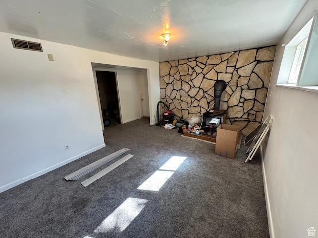 interior space featuring a wood stove, carpet floors, and visible vents