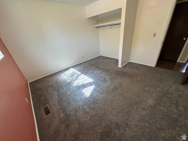 unfurnished bedroom featuring dark carpet, a closet, and baseboards