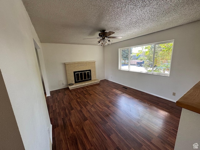 unfurnished living room featuring a ceiling fan, a textured ceiling, baseboards, wood finished floors, and a fireplace