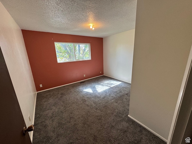 unfurnished room featuring a textured ceiling, carpet floors, and baseboards