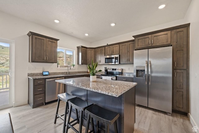 12735 W Kimberly Cir, Tremonton, UT 84337 - kitchen featuring light stone counters, stainless steel appliances, light wood-style flooring, and dark brown cabinetry
