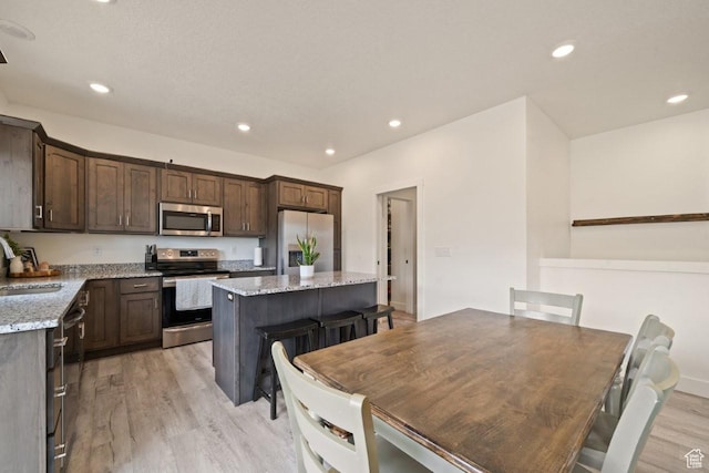 12735 W Kimberly Cir, Tremonton, UT 84337 - kitchen featuring dark brown cabinets, a sink, stainless steel appliances, light wood-style floors, and a kitchen island
