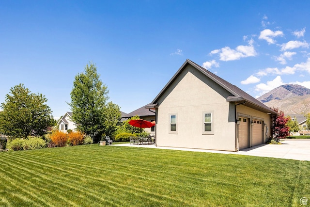 65 W Carnesecca Ct N, Mapleton, UT 84664 - view of side of home featuring a mountain view, concrete driveway, a garage, stucco siding, and a lawn