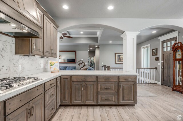 65 W Carnesecca Ct N, Mapleton, UT 84664 - kitchen featuring a peninsula, under cabinet range hood, light countertops, stainless steel gas stovetop, and decorative backsplash