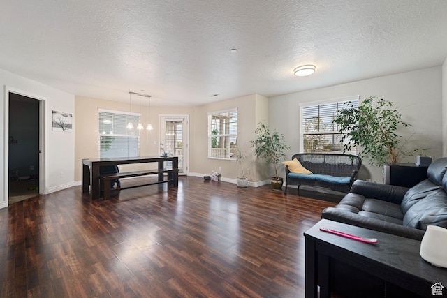 living room with baseboards, a textured ceiling, an inviting chandelier, and dark wood-style floors