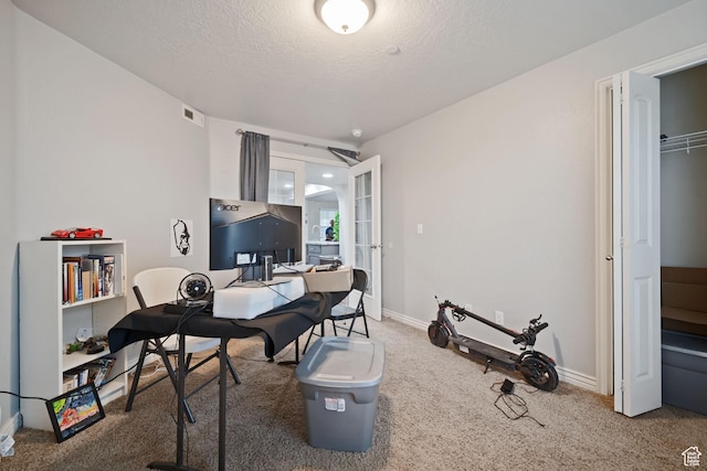 carpeted home office featuring a textured ceiling, baseboards, french doors, and visible vents