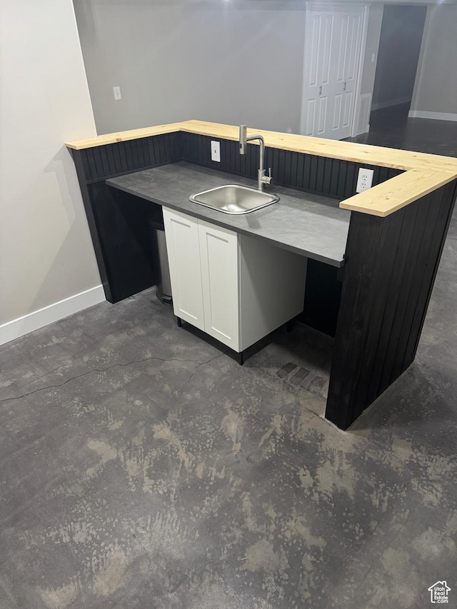 kitchen with white cabinets, baseboards, and a sink