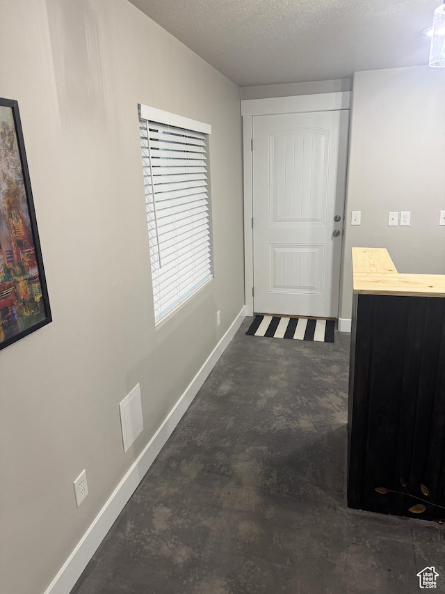 corridor with carpet floors, a textured ceiling, and baseboards